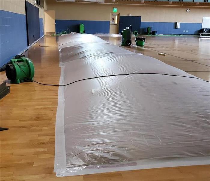 Wood gym floors are wet and now have a grey tarp like tent to concentrate the flow of the high powered fans.
