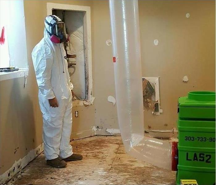 worker with protective gear while removing mold from building