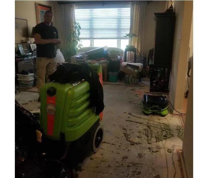 Worker with drying equipment in a living room that has been damaged by water