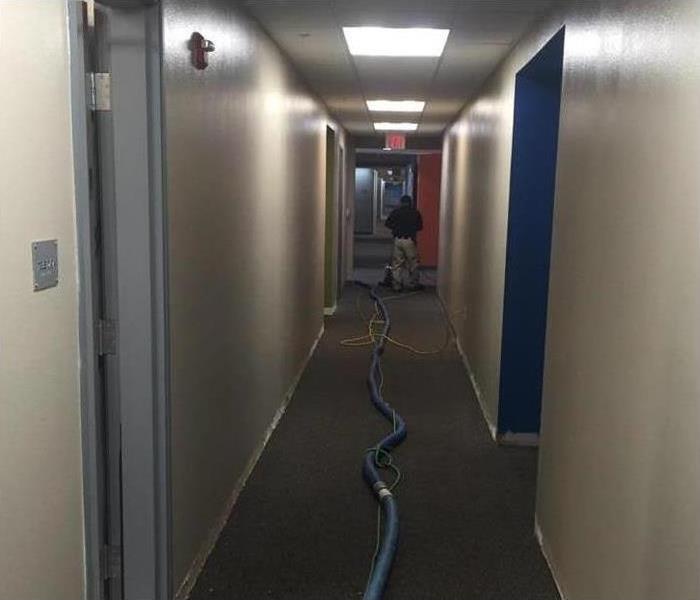 Specialists using a water extraction vacuum in a hallway